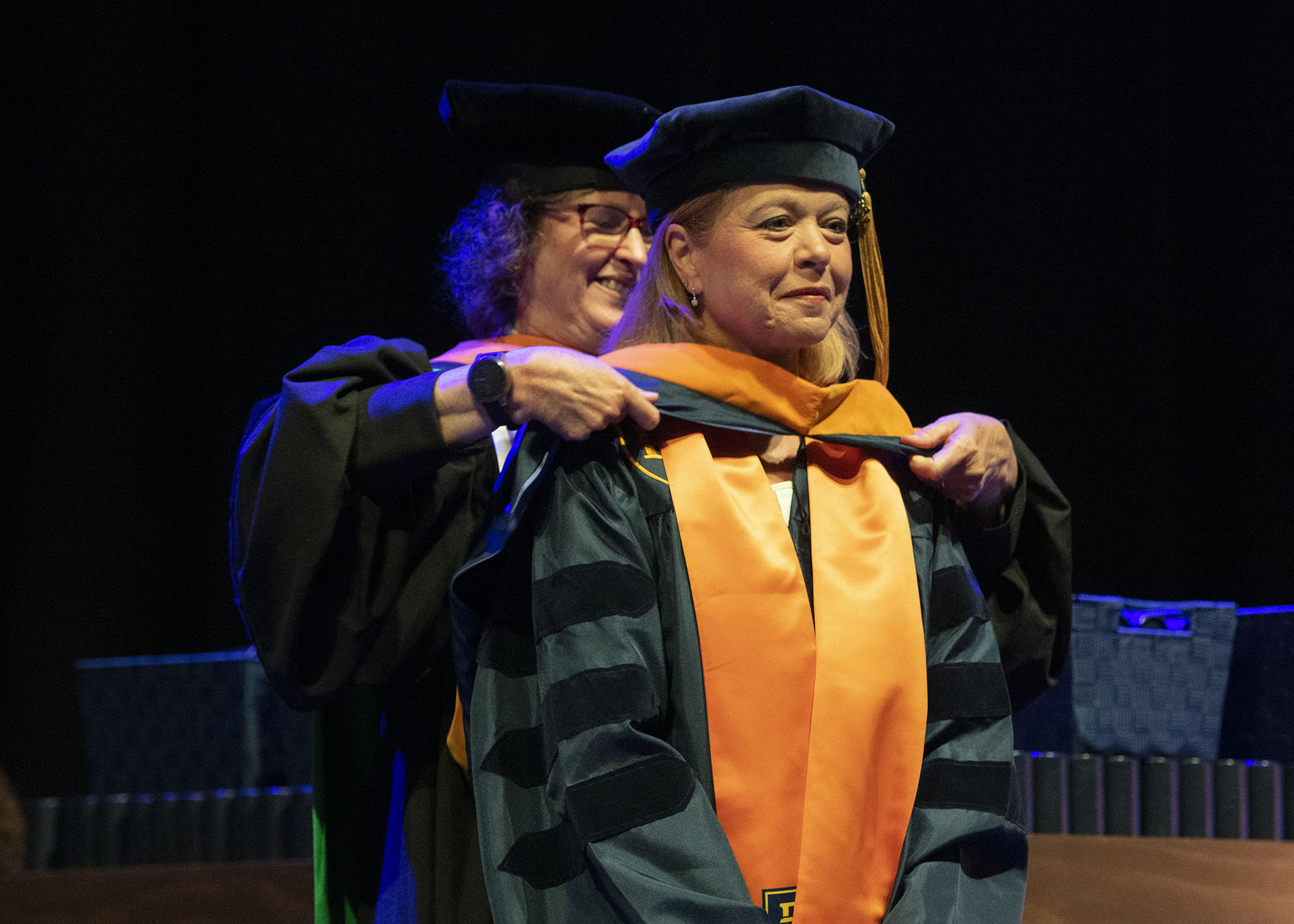 A woman receives her doctoral hood from a representative of the college of nursing at gradaution.