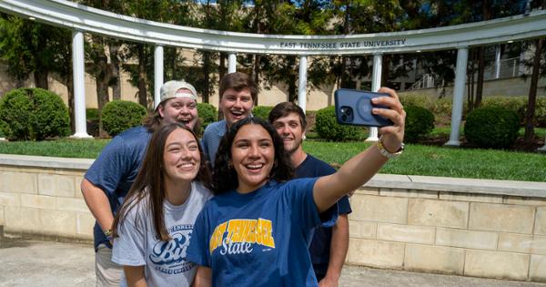 A group of ETSU students huddled together taking a selfie near the ETSU Ampitheatre