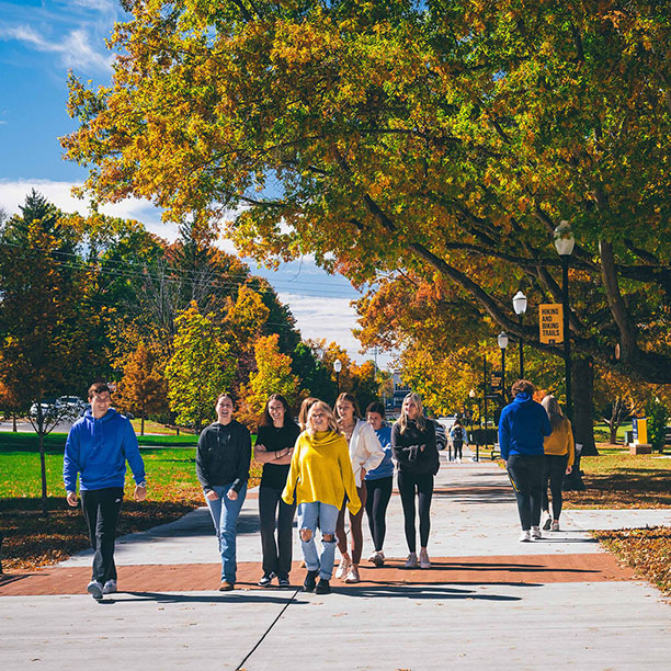 Group of ETSU students walking across campus with fall scenes in the background