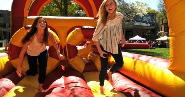 Two students running through a blow-up obsticle course
