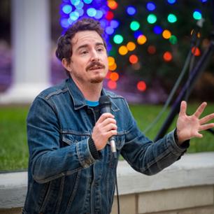 Male student speaking in front of Christmas lights