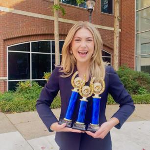 Student holding several trophies
