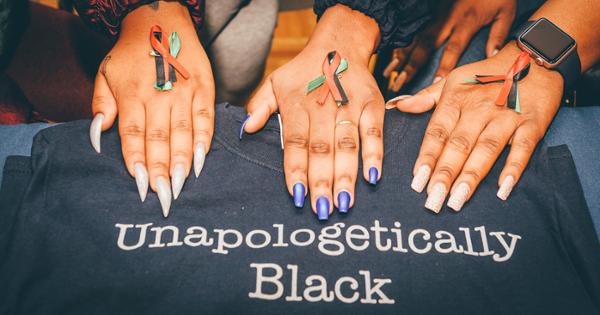 3 hands holding red, black, and green ribbons on a t-shirt that says "Unapologetically Black"