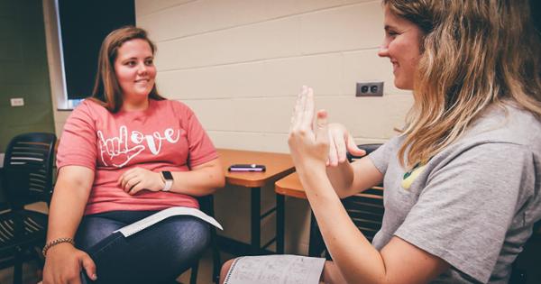 Students practicing their sign language skills together in a classroom setting