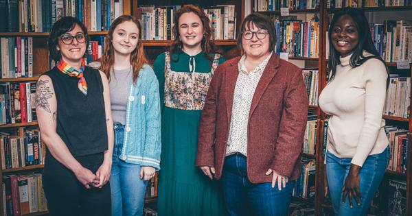 A group of Women's, Gender, and Sexuality Studies professors and students posed together in front of a row of bookshelves