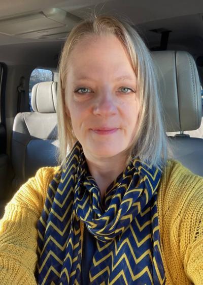 Faculty portrait of Amy Davis with a smile and wearing blue and yellow scarf of Amy Davis