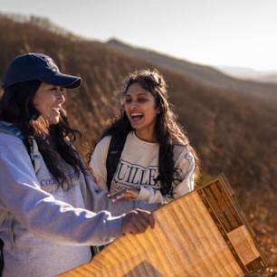 Two medical students laughing and looking at a map while hiking.
