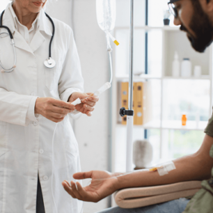 Efficient general practitioner checking solution for chemotherapy of male sitting on exam couch. Young bearded man in casual wear taking dropper while mature female making system review.