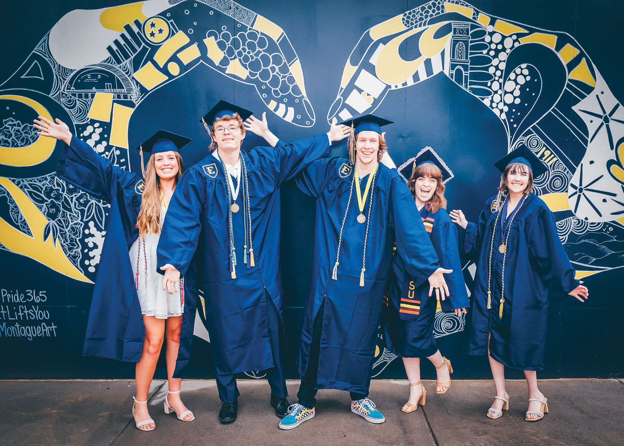 New ETSU grads pose with a heart mural designed by Kelsey Montague.