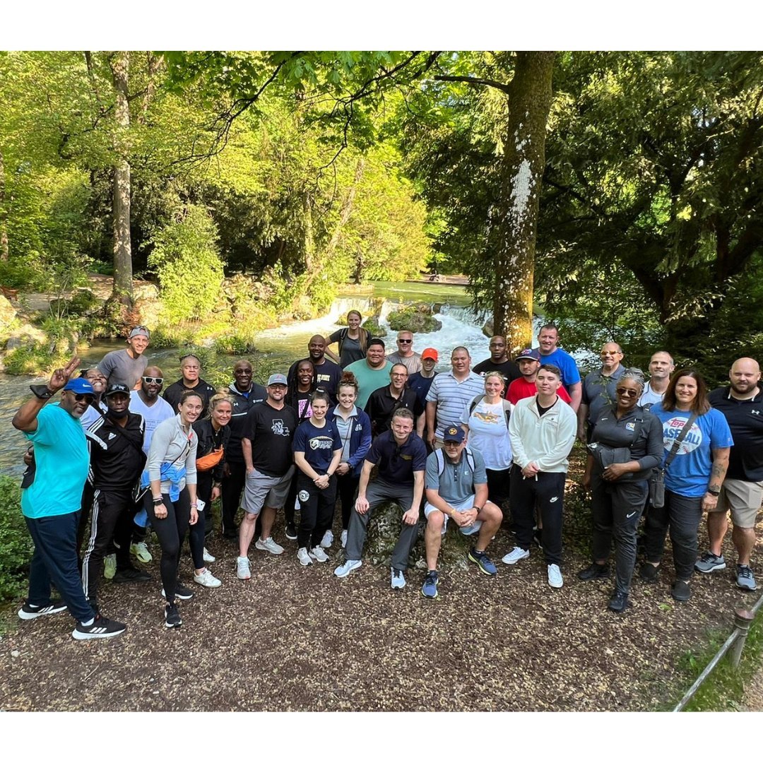 Picture from above a group of people posing for a photo in front of a stream in a forest