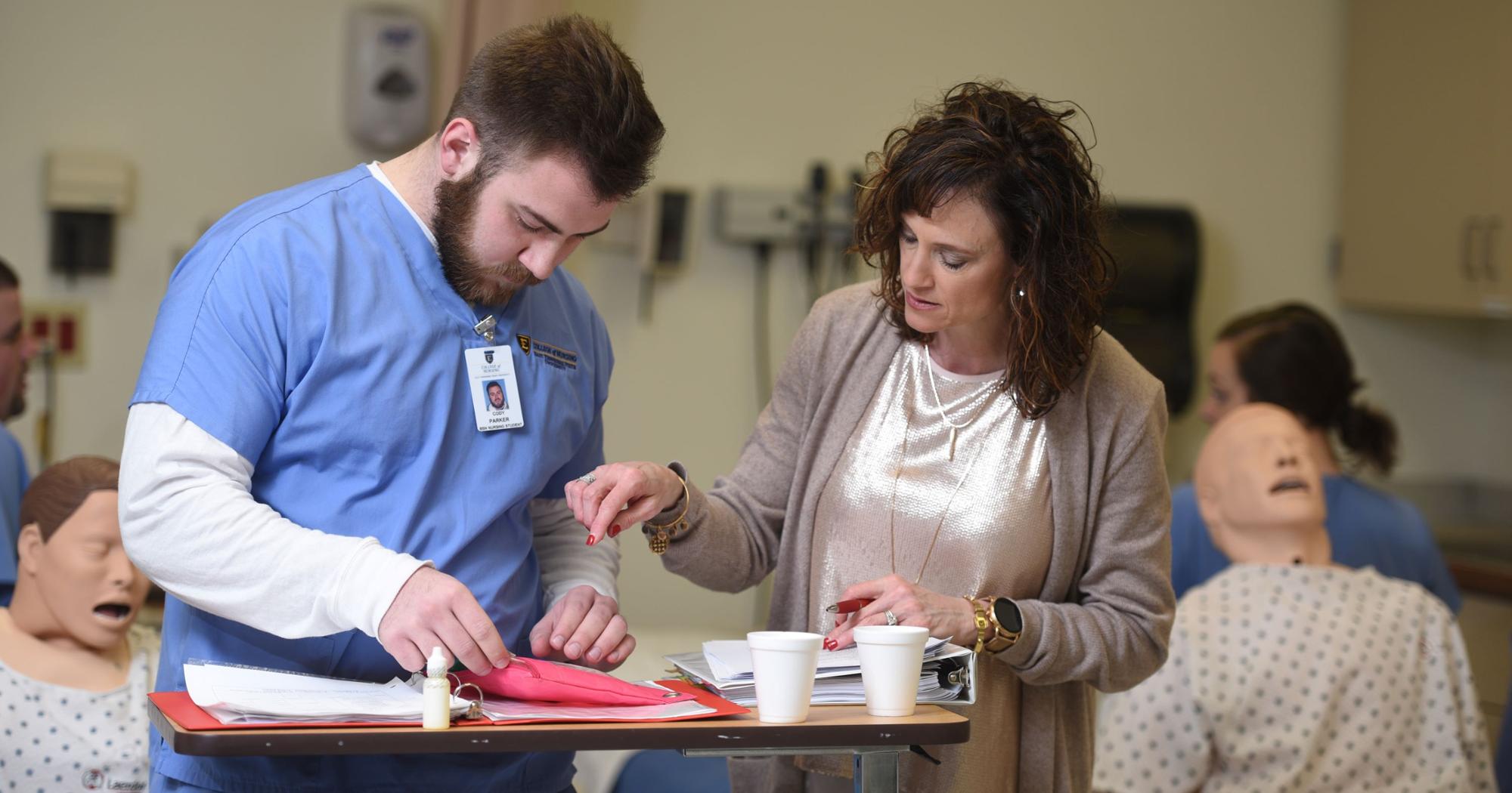 A nursing student receives instruction from a faculty member in the skills lab.