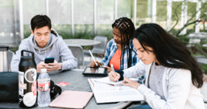 Students of multiple ethnic backgrounds engrossed in work around a table